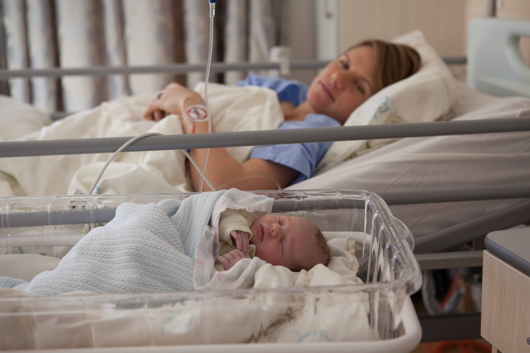 Women in bed and baby in bassinet in Hospital