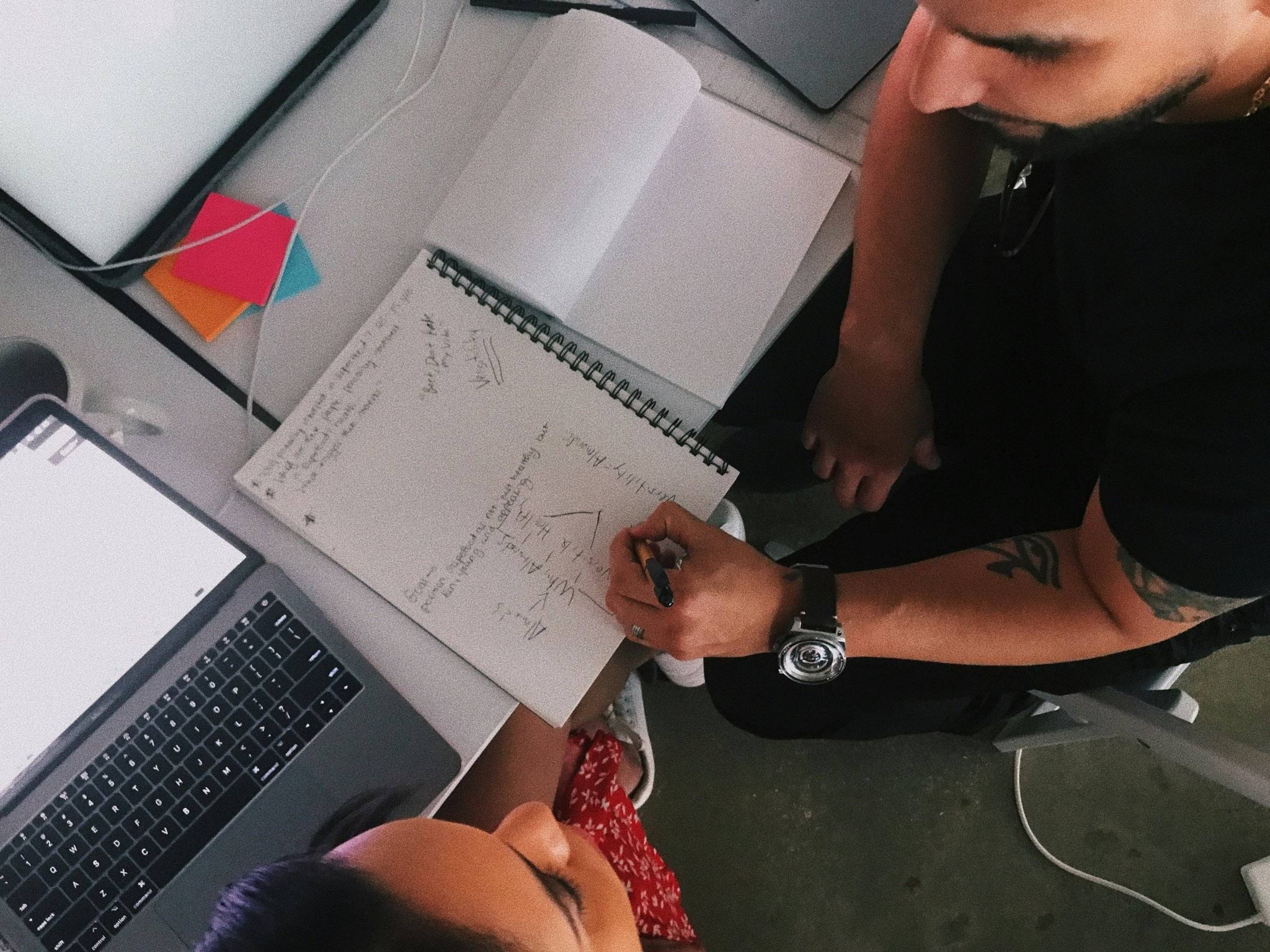 Two individuals in discussion with a notebook